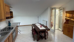 A compact kitchen with a skylight, wooden cabinets, a dining table, and a view of the outside through a sliding door.