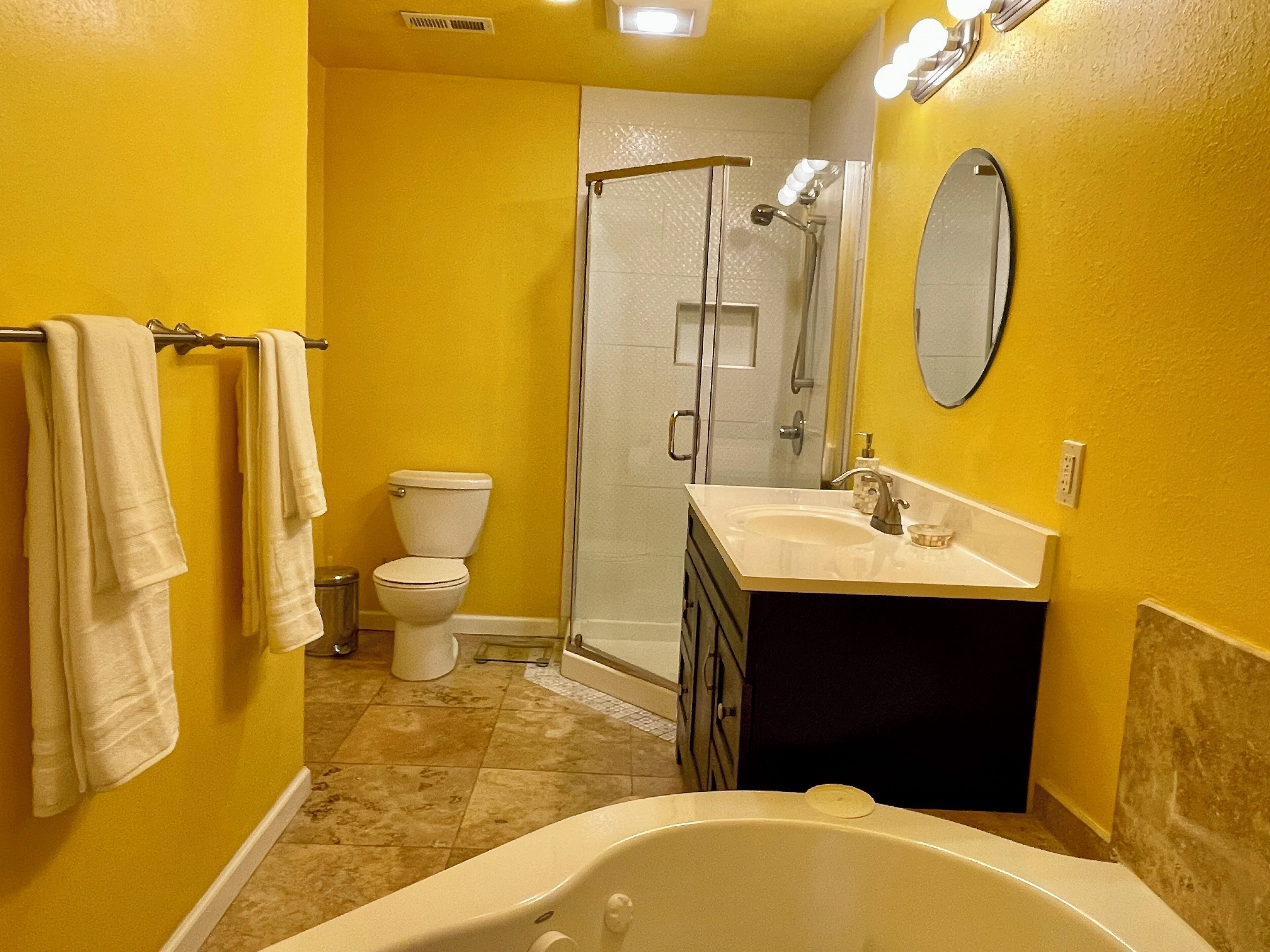 A bathroom with yellow walls, a white toilet, a glass shower enclosure, and a bathtub.