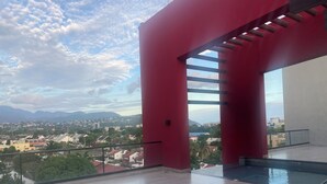 A spacious balcony with a clear view of a cityscape and mountains.