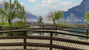 Een houten brug over kalm water, omringd door bomen en bergen op de achtergrond.