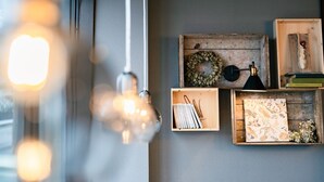A room with a light fixture, a wall-mounted shelf with decorative items, and a wooden box with a lamp. - The Book Lounge Hotel Kani (Kani)