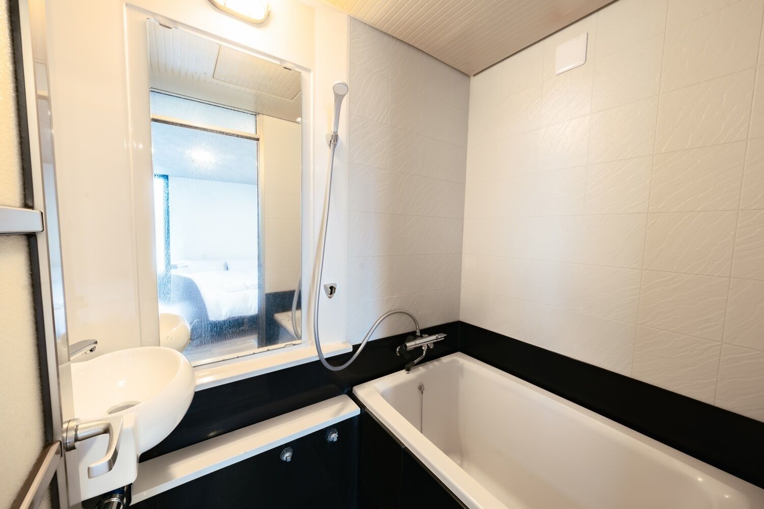 Et badeværelse med et hvidt badekar, en vask og en bruser.