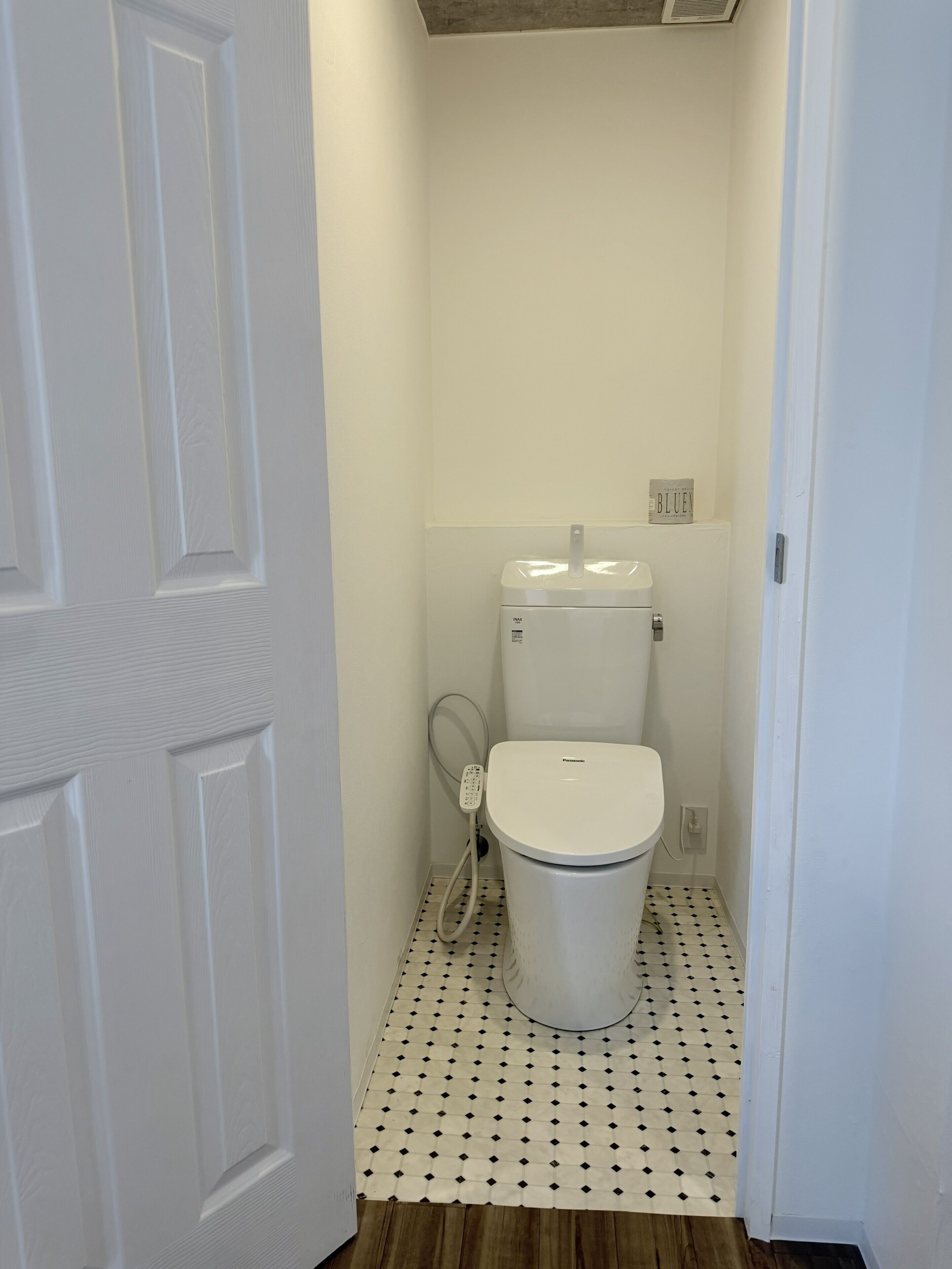 A bathroom with a toilet, a hand dryer, and a small sign on the wall.