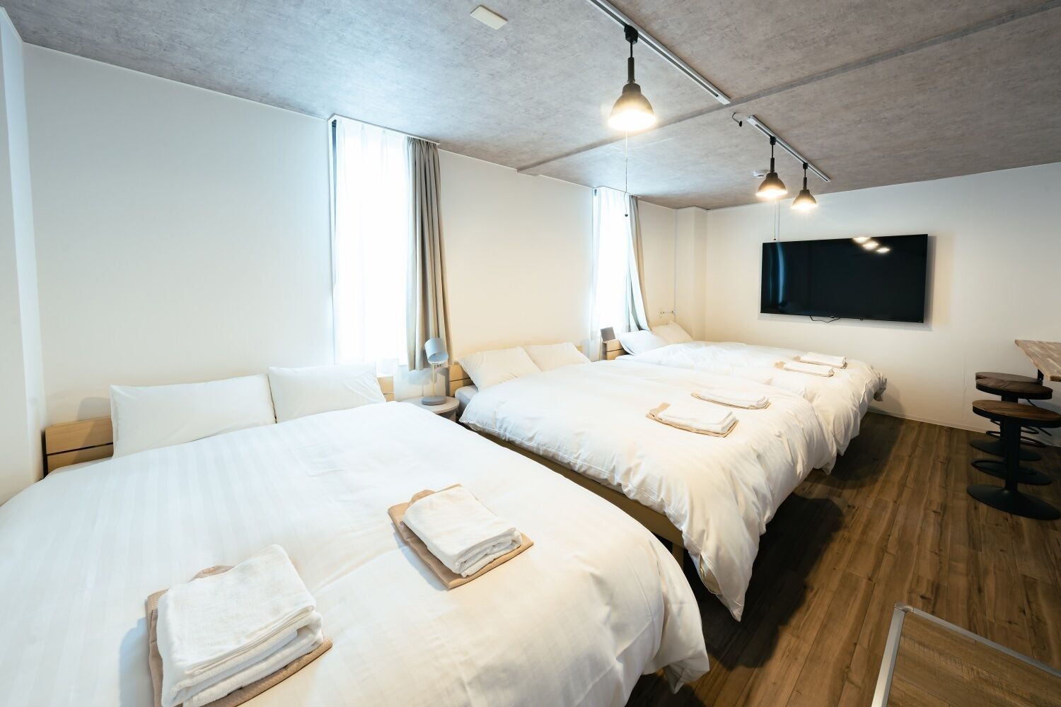 Une chambre d’hôtel avec deux lits, un téléviseur à écran plat et un plancher en bois.