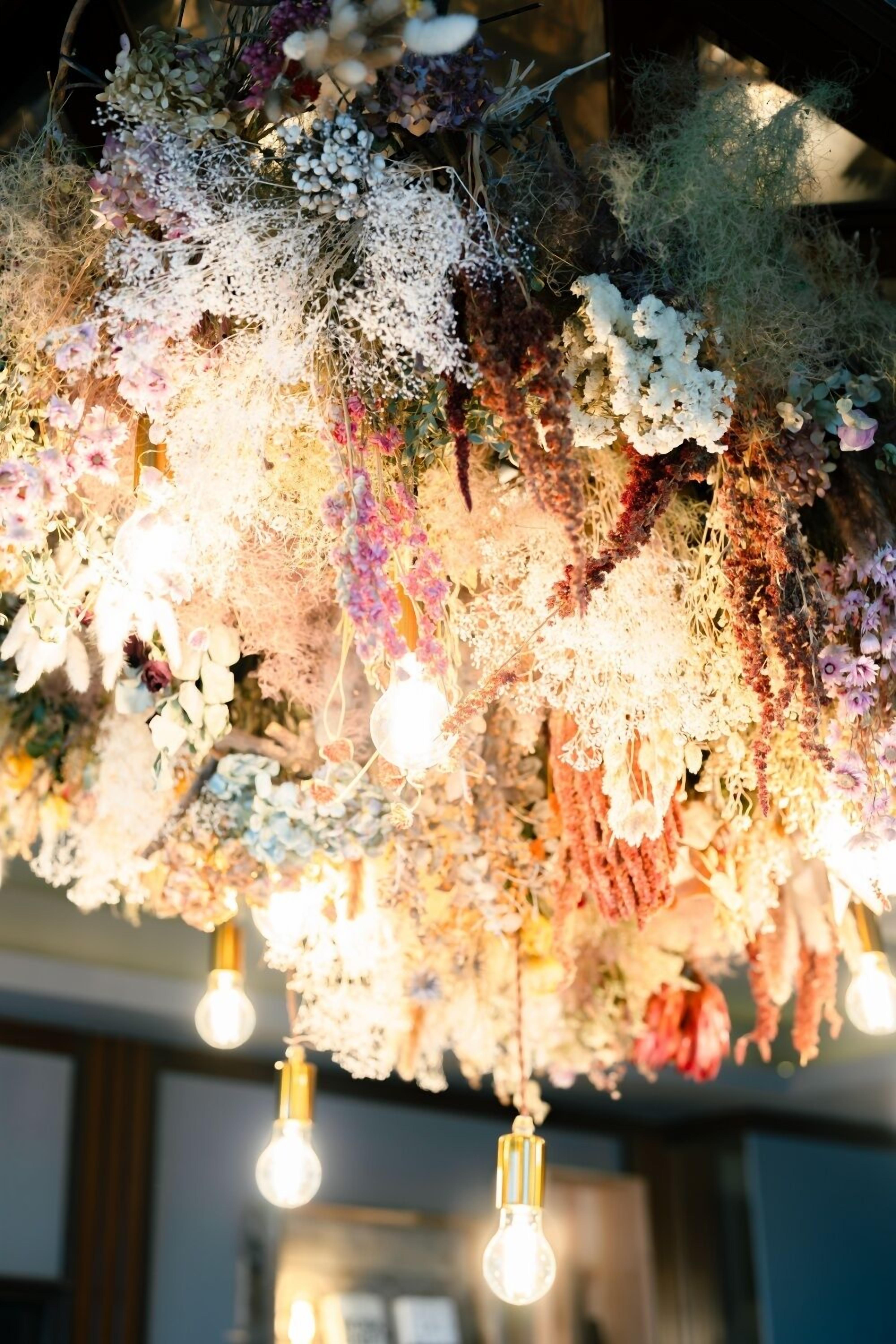A chandelier with multiple light bulbs and a variety of flowers and foliage.