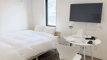 Habitación de hotel moderna con cama, escritorio, silla, televisor de pantalla plana y ventana.