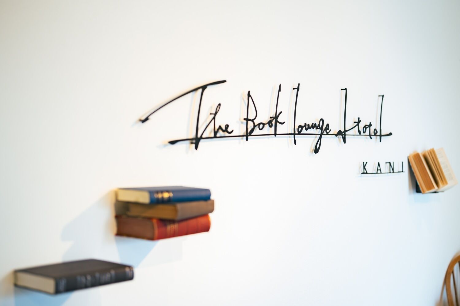 A wall with the text "The Book Lounge" and a stack of books.