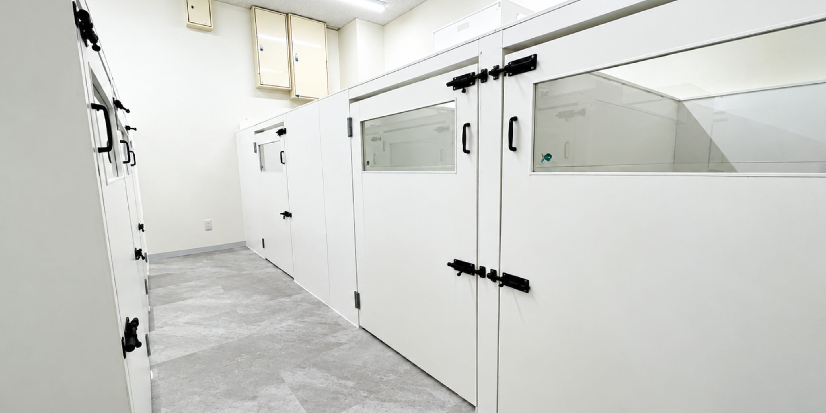 A corridor with white cabinets, a tiled floor, and a ceiling with recessed lighting.