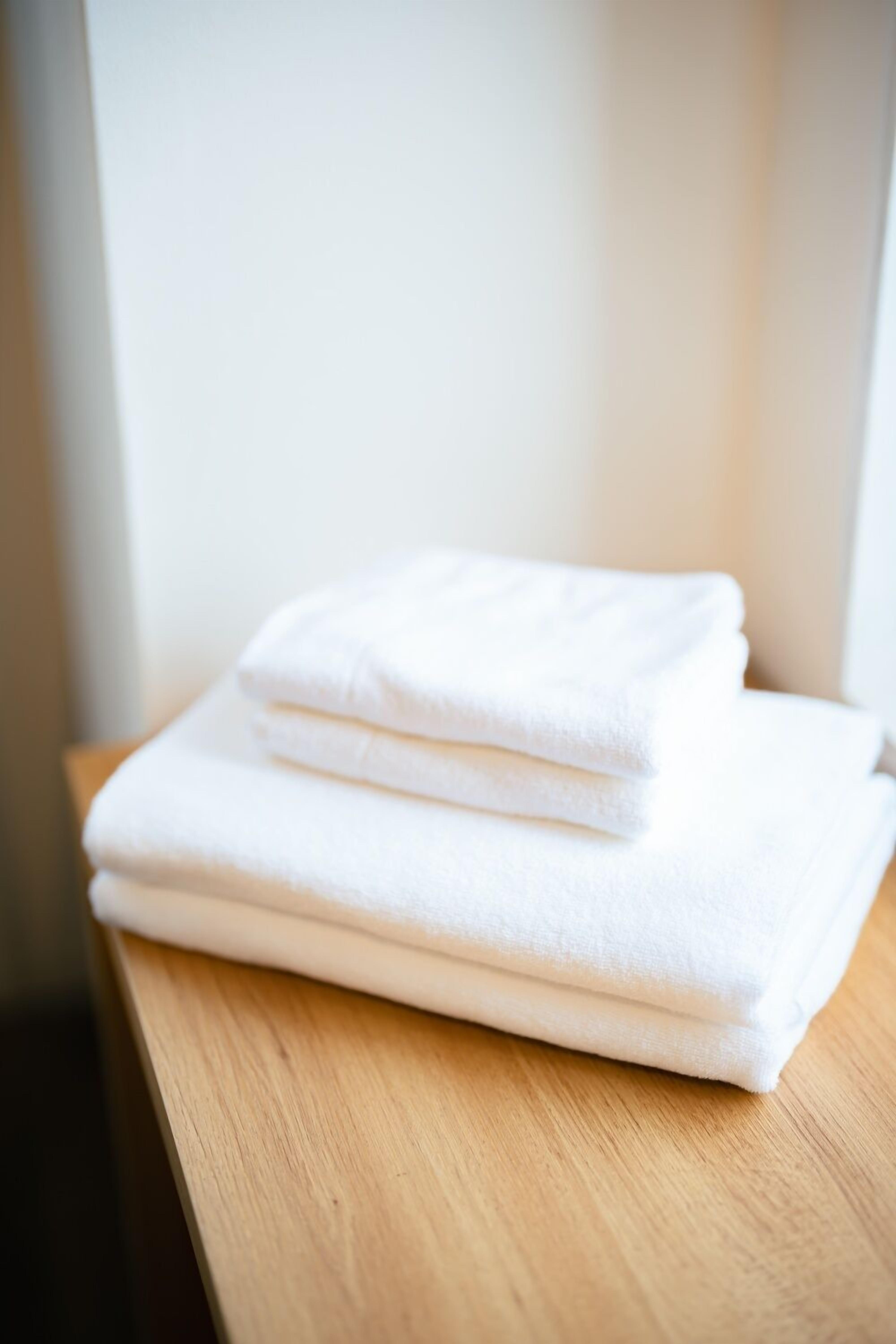 A stack of white towels on a wooden surface.
