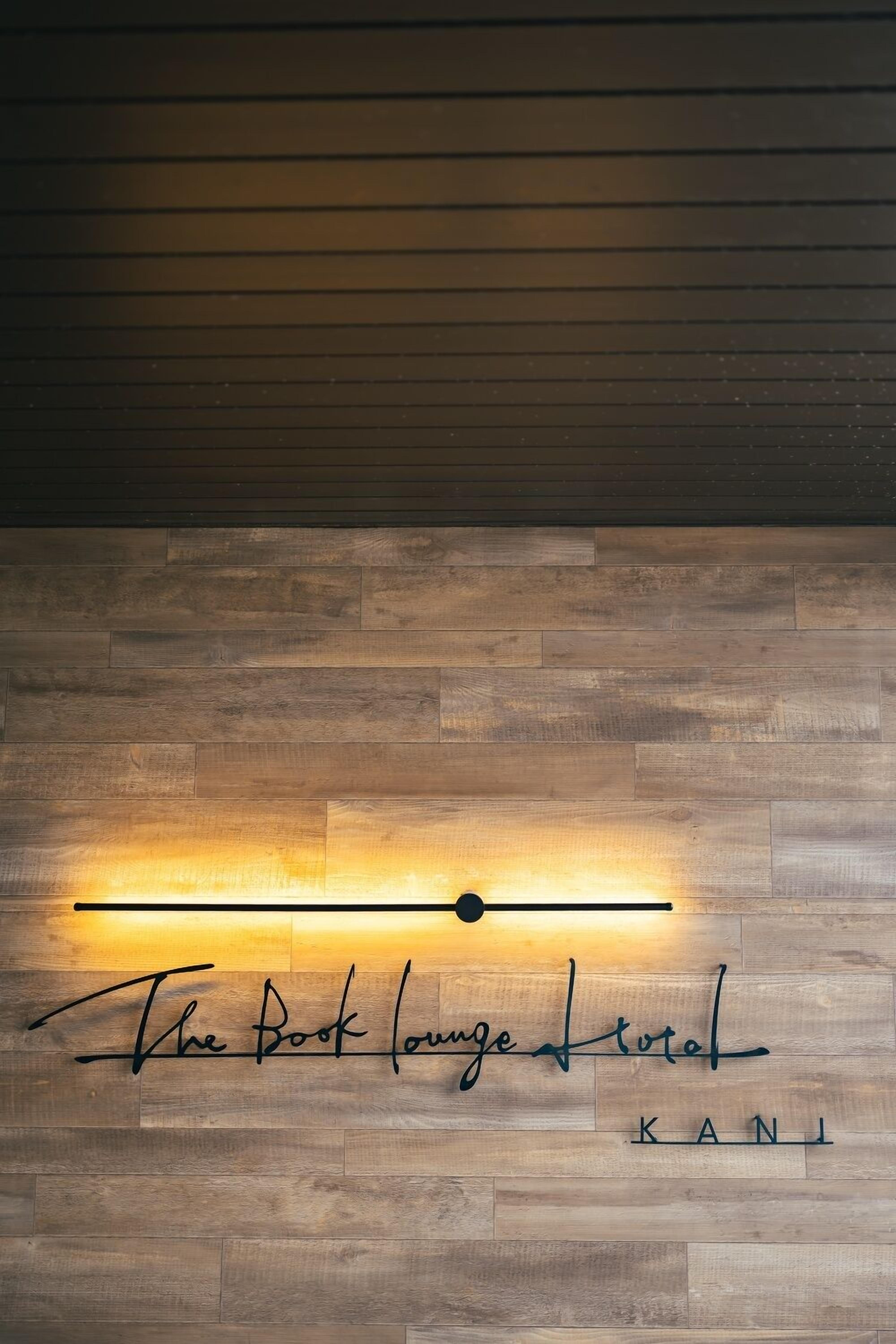 Una pared con diseño de panel de madera y un letrero de neón que dice "The Book Lounge Total KANI".