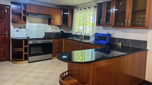 Une cuisine avec des meubles de rangement en bois, un plan de travail noir, une cuisinière et un four à micro-ondes.