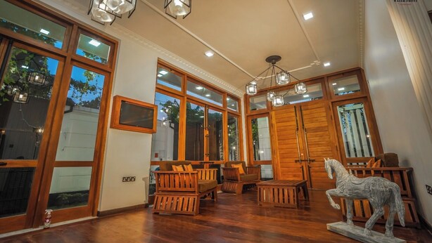 Una habitación amplia con ventanas grandes, muebles de madera y una estatua decorativa de un caballo.