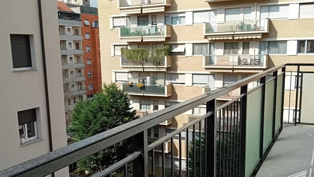 Un immeuble résidentiel à plusieurs étages, doté de balcons, d’une entrée sécurisée et d’un arbre bien visible.
