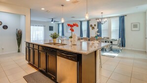 Una cocina moderna con una isla central, lavavajillas integrado y un comedor con candelabro.