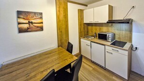 Une cuisine de taille réduite avec une table en bois, des placards blancs, un four à micro-ondes et un évier.