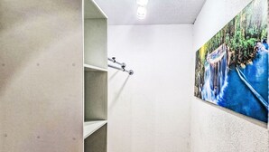 Un couloir avec un escalier menant à une pièce, une porte portant un numéro et un mur orné d’un tableau.