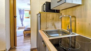 A compact kitchen with a sink, a small refrigerator, and wooden cabinets.