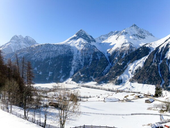 A snow-covered mountain landscape with a small village and a clear sky.