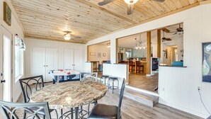 A spacious dining area with a marble table and metal chairs, a kitchen in the background, and wooden ceiling beams. - Crappie Fishing On Site! Lake Tawakoni Escape (East Tawakoni)