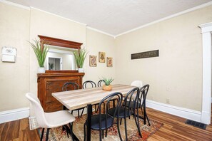 A dining area with a wooden table, black chairs, a mirror, and a potted plant.