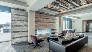 A modern lobby with a large seating area, a patterned wall, and a view of the outside.