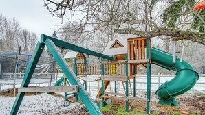 Un parque infantil con tobogán y columpios, rodeado de tierra nevada.