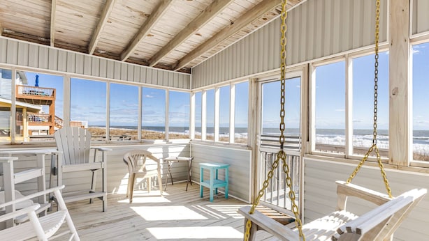 A wooden deck with a swing chair, a small stool, and a rocking chair.