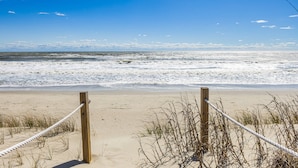 A sandy beach with a rope barrier and wooden posts.