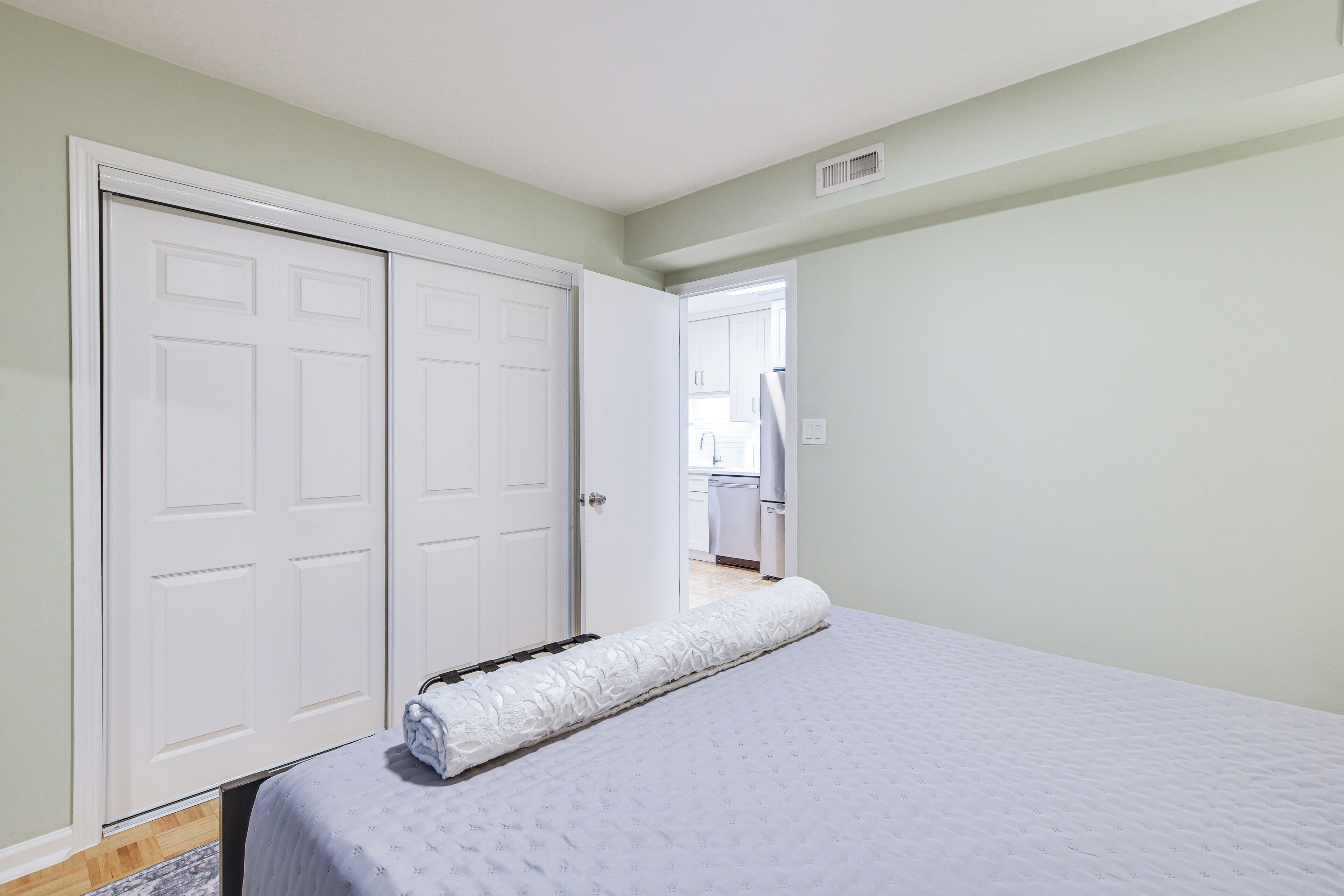 A bedroom with a large bed, a white wardrobe, and a door leading to a bathroom.