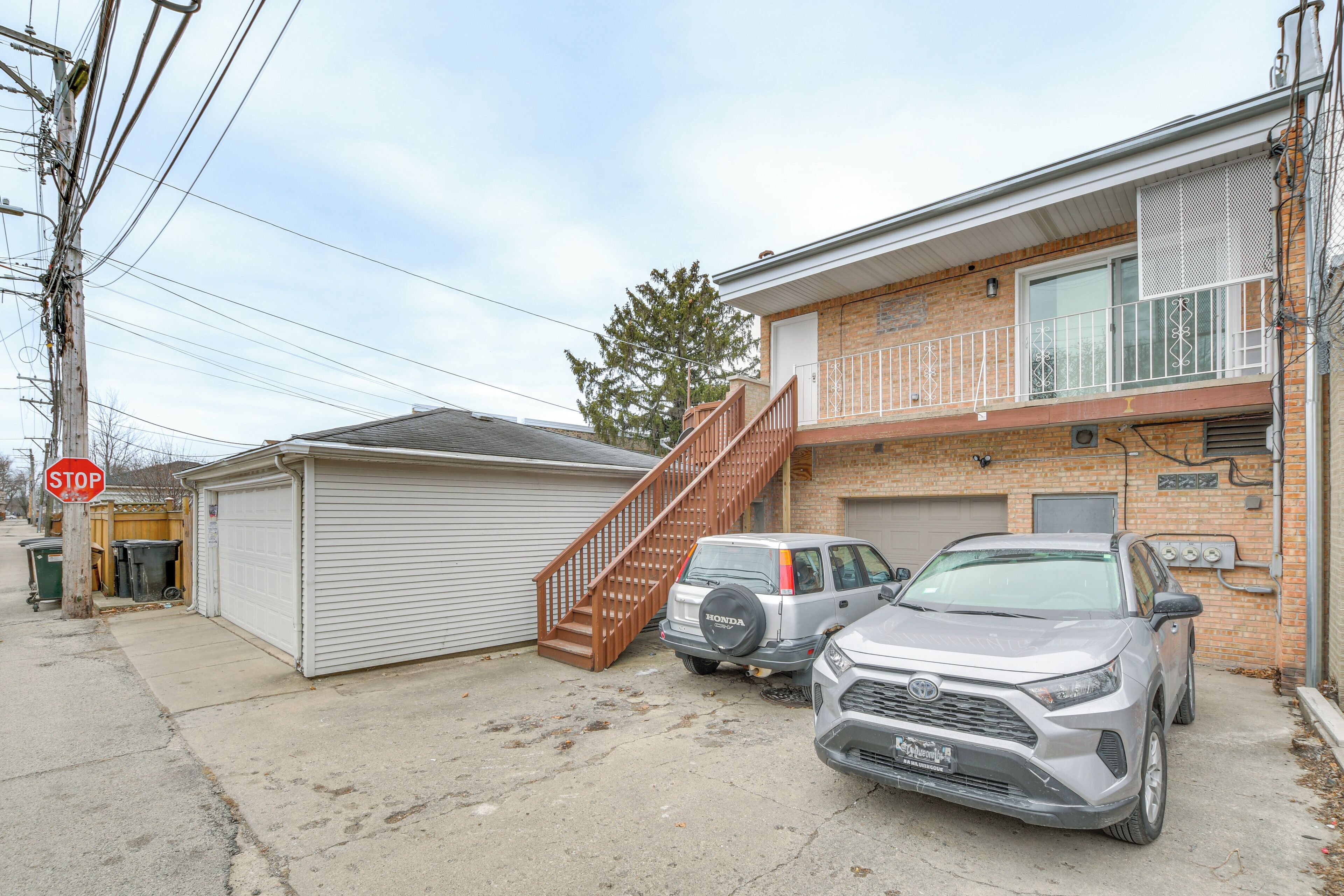 A two-story building with a garage, a staircase, and two parked cars.