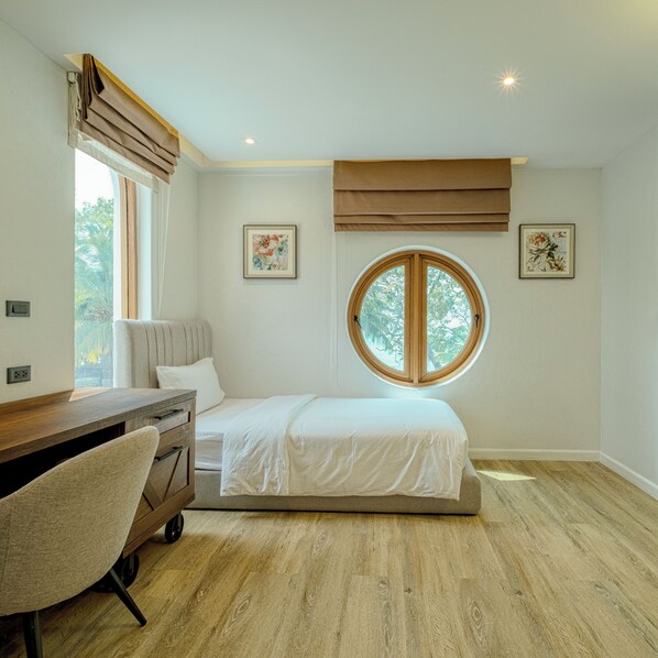 A bedroom with a bed, a desk, and a window.