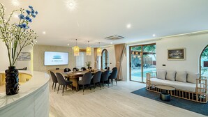 Un comedor moderno con una mesa de madera, sillas y una pantalla grande mostrando 'A Dream Villas'.