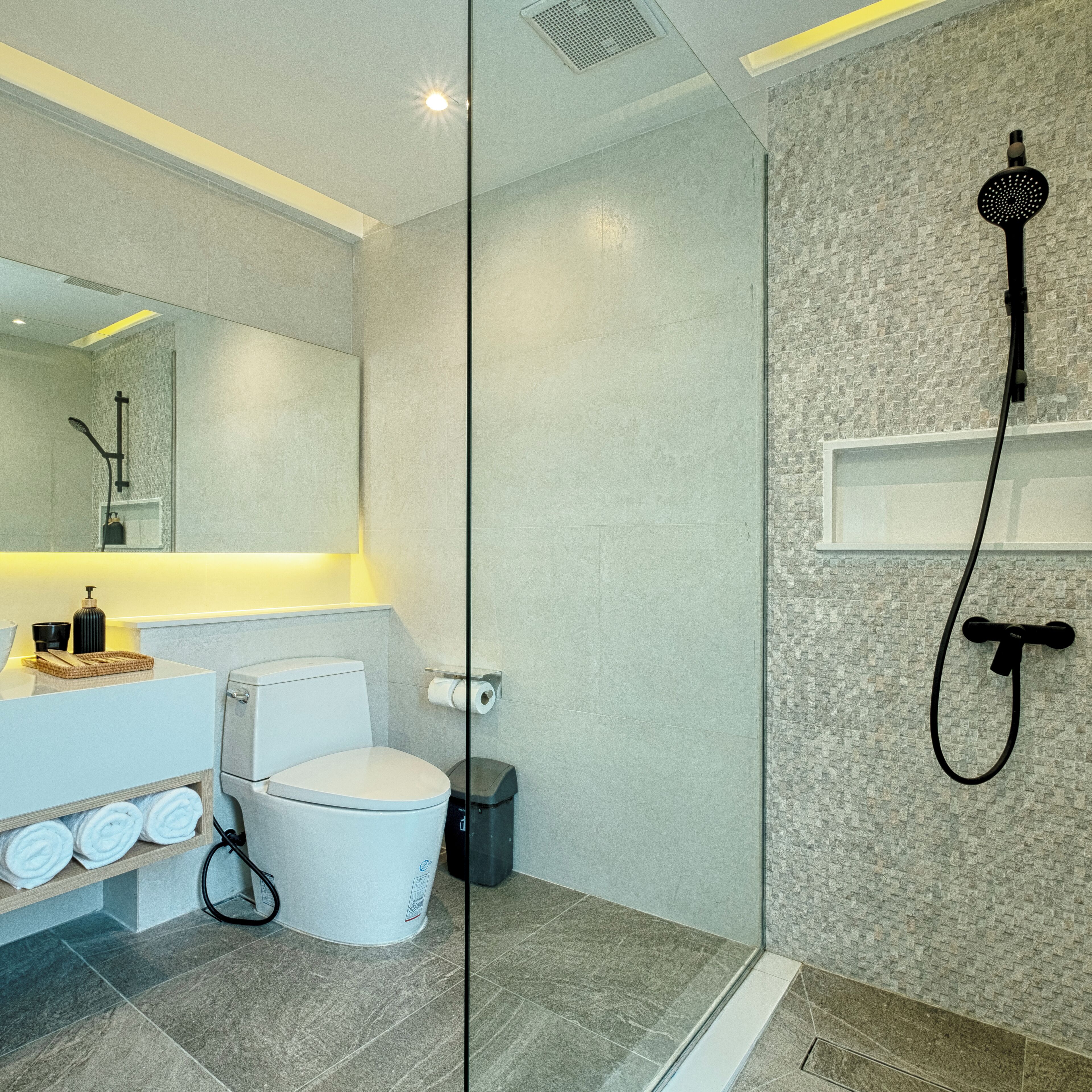 Een moderne badkamer met een glazen douchecabine, een wit toilet en een wastafel met spiegel.