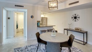 A modern dining area with a round table, dark chairs, and a light wood finish. - 8 Mi to Beach: Modern Condo in Fort Myers! (Fort Myers)