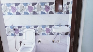 A small bathroom with a toilet, a sink, and a shower.