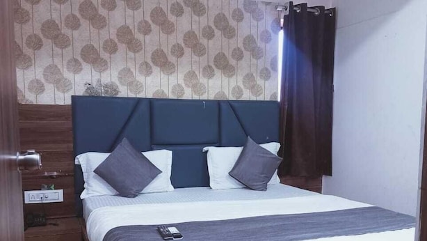 A bedroom with a wooden bed, a headboard, a nightstand, a wall-mounted air conditioner, and a patterned wallpaper.