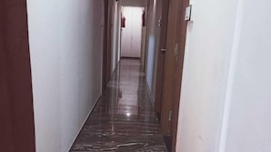 A hallway with a shiny, dark marble floor, white walls, and wooden doors.