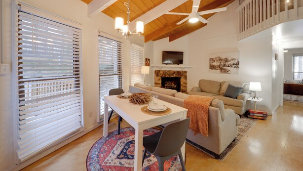 A spacious living area with a high ceiling, a fireplace, a sofa, a dining table with chairs, and a television. - < 1 Mi to Beech Mtn! All-Season Outdoor Retreat (Beech Mountain)