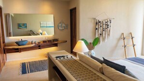 A hotel room with a bed, a bench, a small table with a bowl, a lamp, a wall-mounted rack, and a ladder. - Amazing Nicole 1 Ocean Views (Troncones)