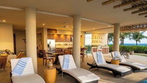 A poolside area with lounge chairs, a dining area, and a view of the ocean. - Amazing Nicole 1 Ocean Views (Troncones)