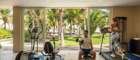 A gym with exercise equipment, a treadmill, and a bench.