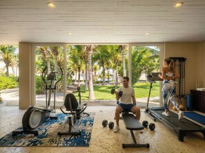 Une salle de sport équipée de matériel d’exercice, d’un tapis de course et d’un banc.