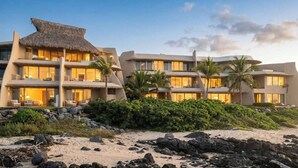 A beachfront hotel with multiple balconies, palm trees, and a thatched roof structure. - Amazing Nicole 1 Ocean Views (Troncones)