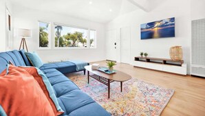 Ein modernes Wohnzimmer mit einem blauen Ecksofa, einem Couchtisch und einem bunten Teppich.
