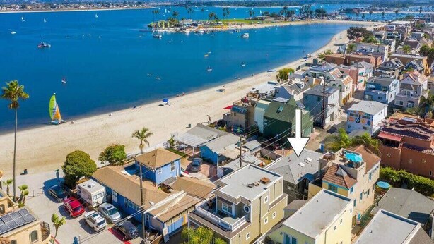 A coastal town with a beach, boats, and residential buildings. - Affordable Mission Beach Condo – Views & Surf Gear (San Diego)