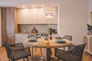 A modern dining area with a round table, black chairs, and a hanging light fixture.