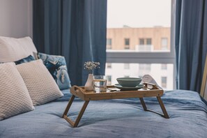 Une table de chevet en bois sur laquelle se trouvent un verre d’eau, un bol et un vase avec des fleurs.