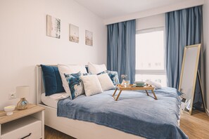 A modern bedroom with a bed, bedside table, and a window with curtains.