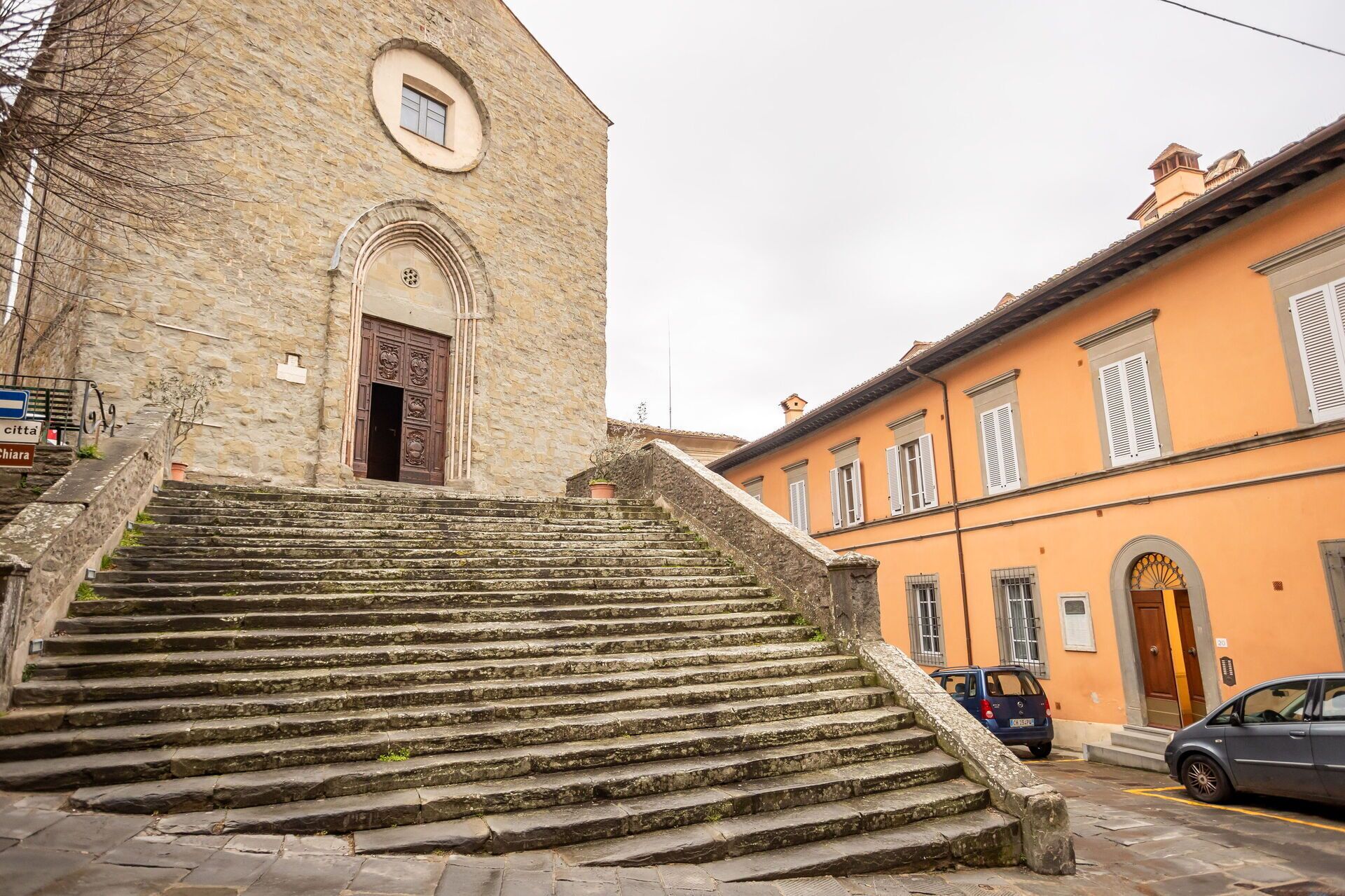 Eine Steintreppe führt zu einem Gebäude mit einem traditionellen Rundbogenportal.