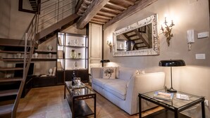 A living room with a staircase, a sofa, a glass coffee table, and a bookshelf. - Apartment in Cortona with 2 bedrooms sleeps 4 (Cortona)